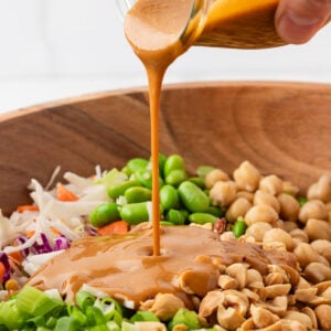Creamy peanut dressing being poured over quinoa edamame salad.