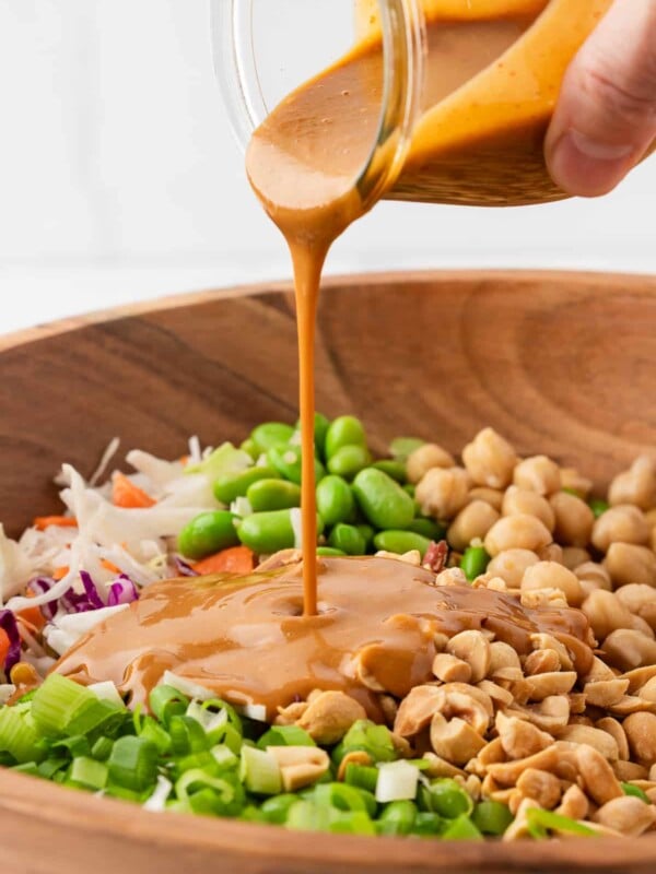 Creamy peanut dressing being poured over quinoa edamame salad.