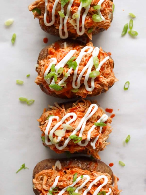 4 buffalo chicken stuffed sweet potatoes on a sheet tray with parchment paper