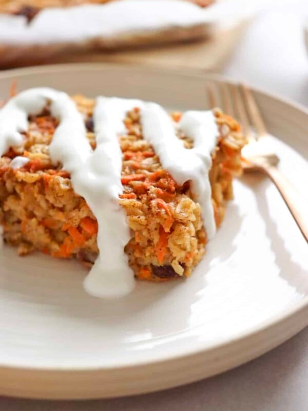 a slice of carrot cake baked oats drizzled with greek yogurt