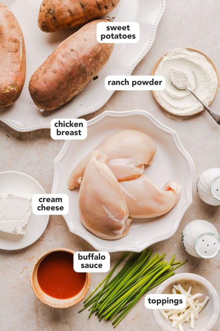 Ingredients for buffalo chicken sweet potatoes in small bowls on a marble counter.