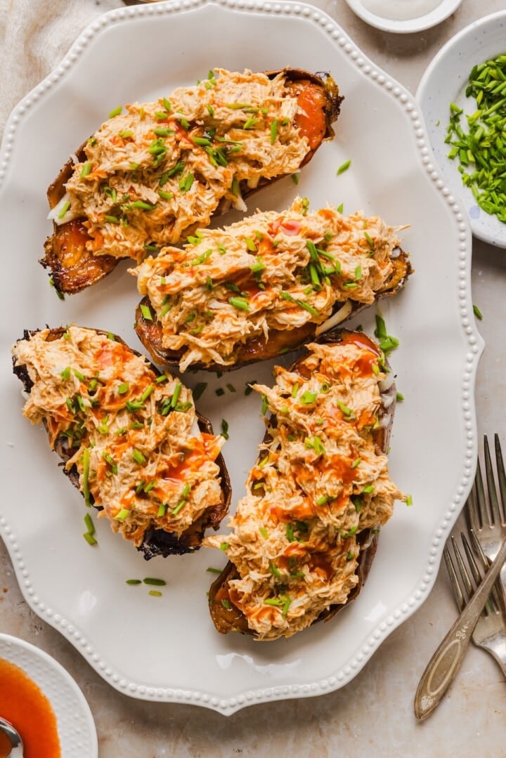 Buffalo chicken stuffed sweet potatoes on a white serving tray.