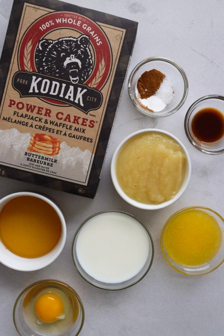Ingredients for kodiak cakes muffins without banana displayed in small bowls on a white counter