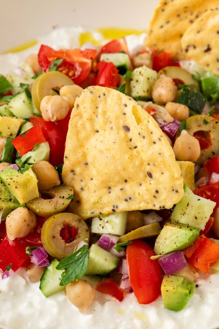Cottage cheese greek salad in a bowl with a tortilla chip, read to scoop.