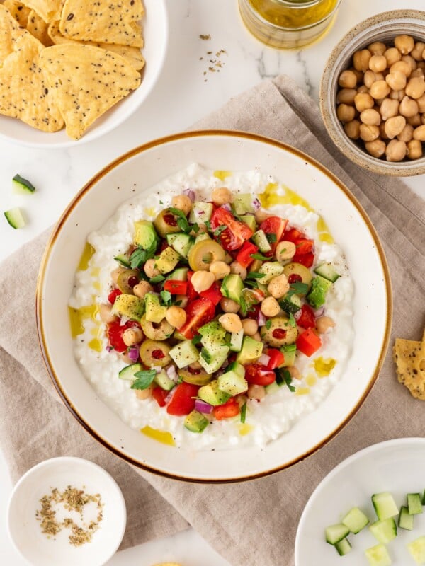 Greek-inspired cottage cheese salad in a bowl next to tortilla chips.