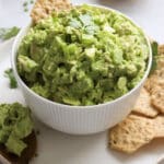 Green goddess chicken salad in a white bowl, served with crackers and herbs