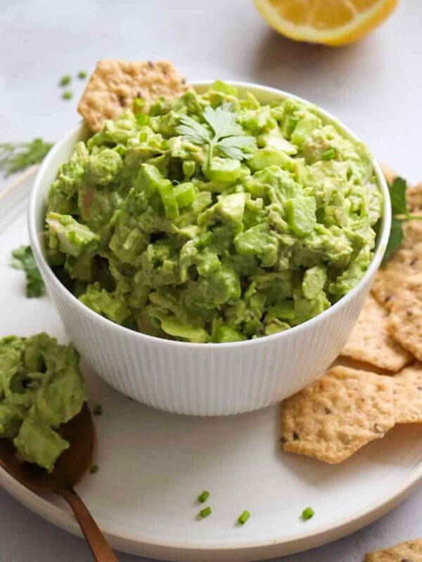 Green goddess chicken salad in a white bowl, served with crackers and herbs