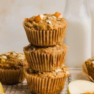 Apple cinnamon oatmeal muffins piled on a cooling rack.