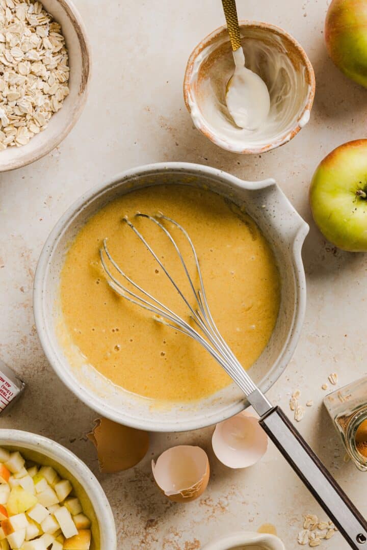 Wet ingredients for apple cinnamon oat muffins in a large mixing bowl.