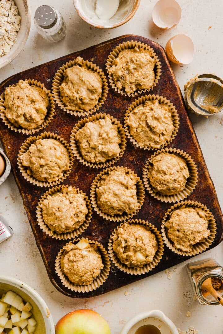 Raw apple cinnamon oat muffins in a baking pan.