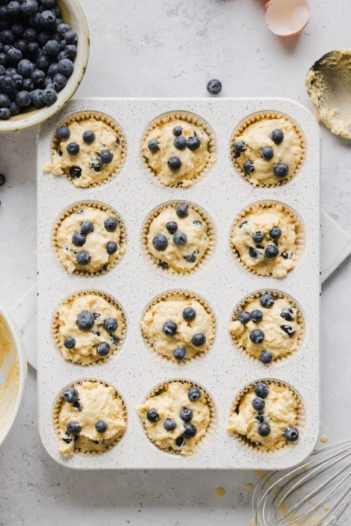Raw protein blueberry muffins in prepared baking pan.