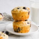Two high-protein blueberry muffins stacked on a white plate.