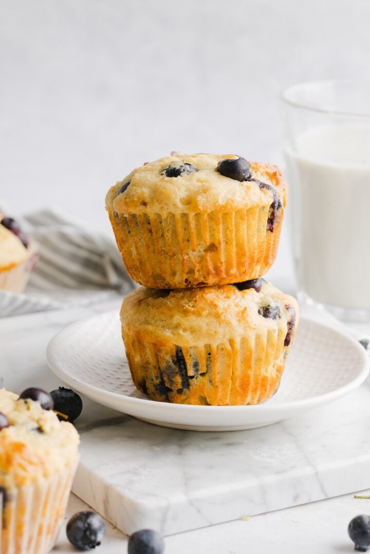 Two high-protein blueberry muffins stacked on a white plate.
