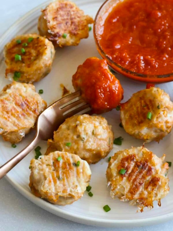 White plate with baked chicken meatballs and marinara dipping sauce