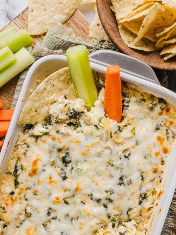 Healthy spinach artichoke dip in a grey baking dish with tortilla chips.