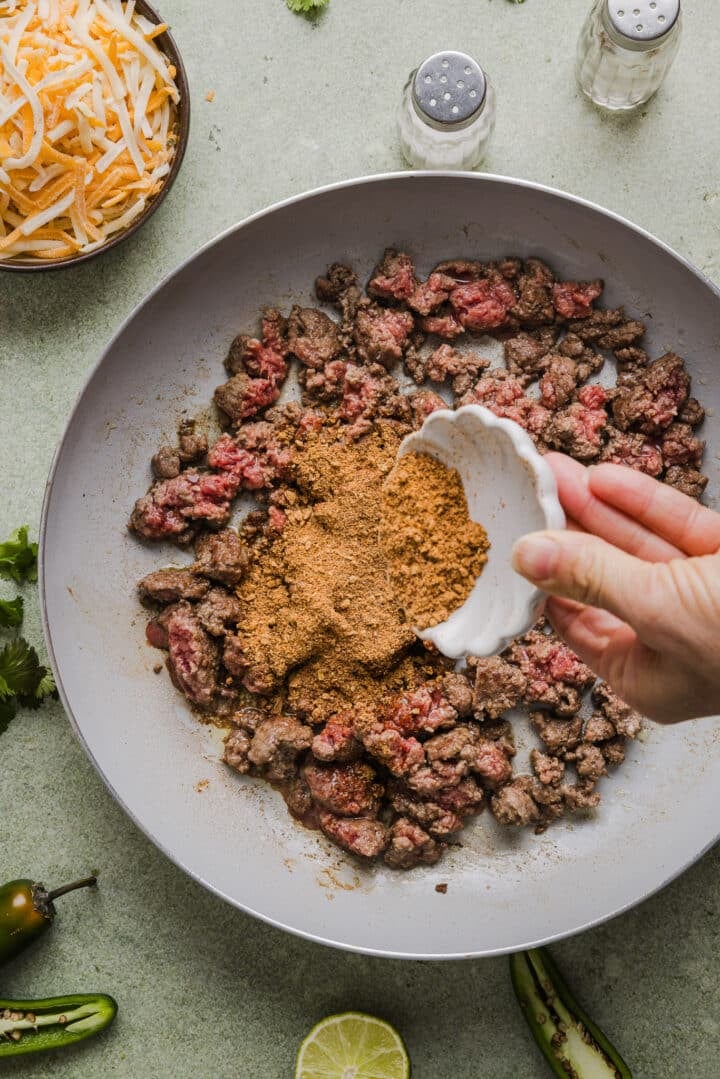Ground beef with taco seasoning being poured over top.