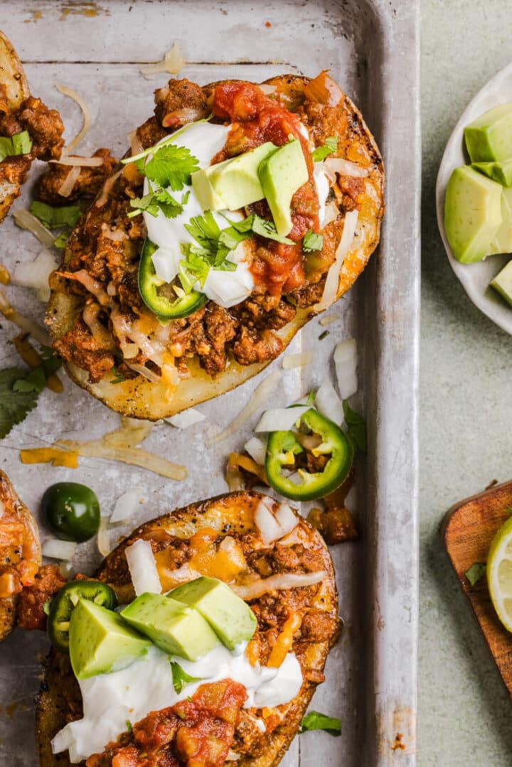 Taco baked potatoes topped with sour cream and avocado.