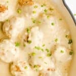 Chicken swedish meatballs and gravy garnished with chives in a white skillet