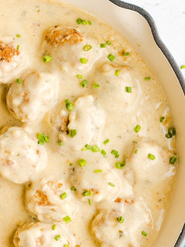 Chicken swedish meatballs and gravy garnished with chives in a white skillet