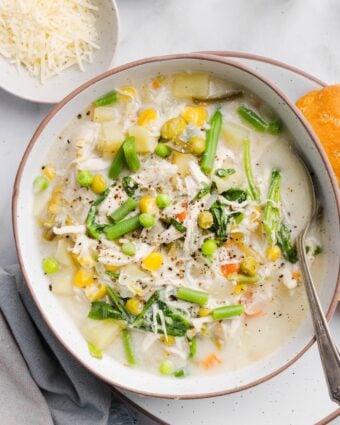 Chicken pot pie soup in a shallow white bowl, served with a biscuit