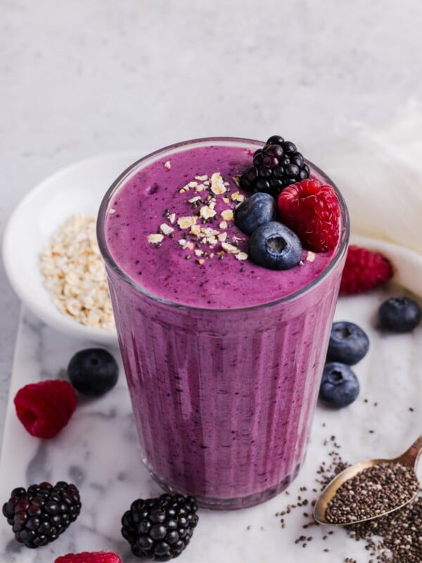 High fiber fruit smoothie in a tall glass, topped with fresh berries and oats