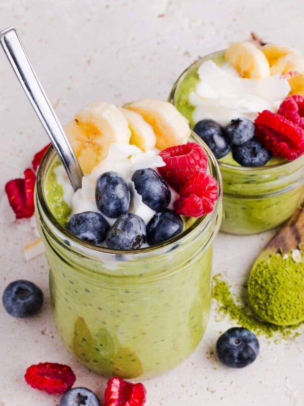 Two jars of matcha overnight oats topped with fruit and yogurt
