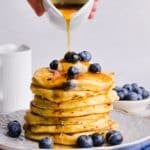 Stack of blueberry cottage cheese pancakes with maple syrup being poured on top