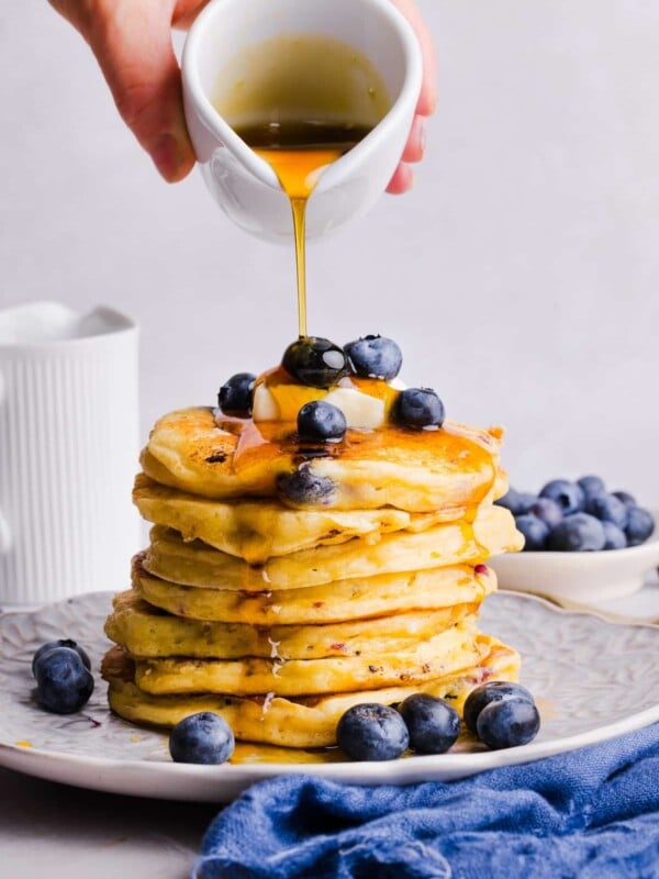 Stack of blueberry cottage cheese pancakes with maple syrup being poured on top