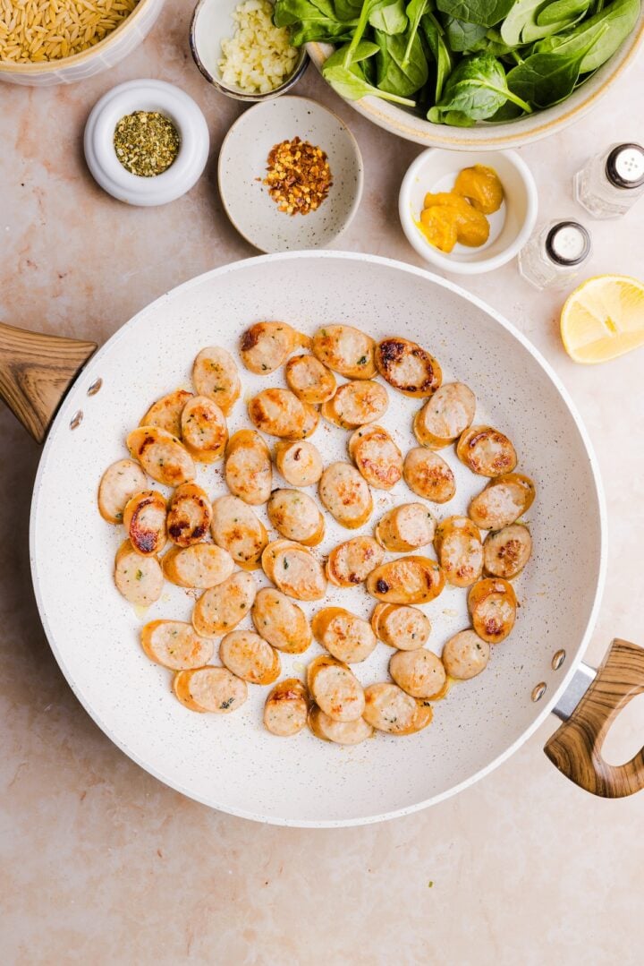 Sliced chicken sausage cooked in a large, white pot