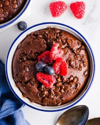 Birdseye photo of a ramekin filled with chocolate baked oatmeal, topped with raspberries and blueberries