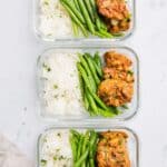 3 rectangular glass containers with rice, green beans, and meal prep chicken thighs