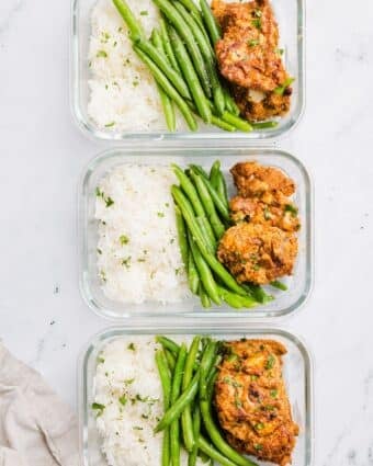 3 rectangular glass containers with rice, green beans, and meal prep chicken thighs