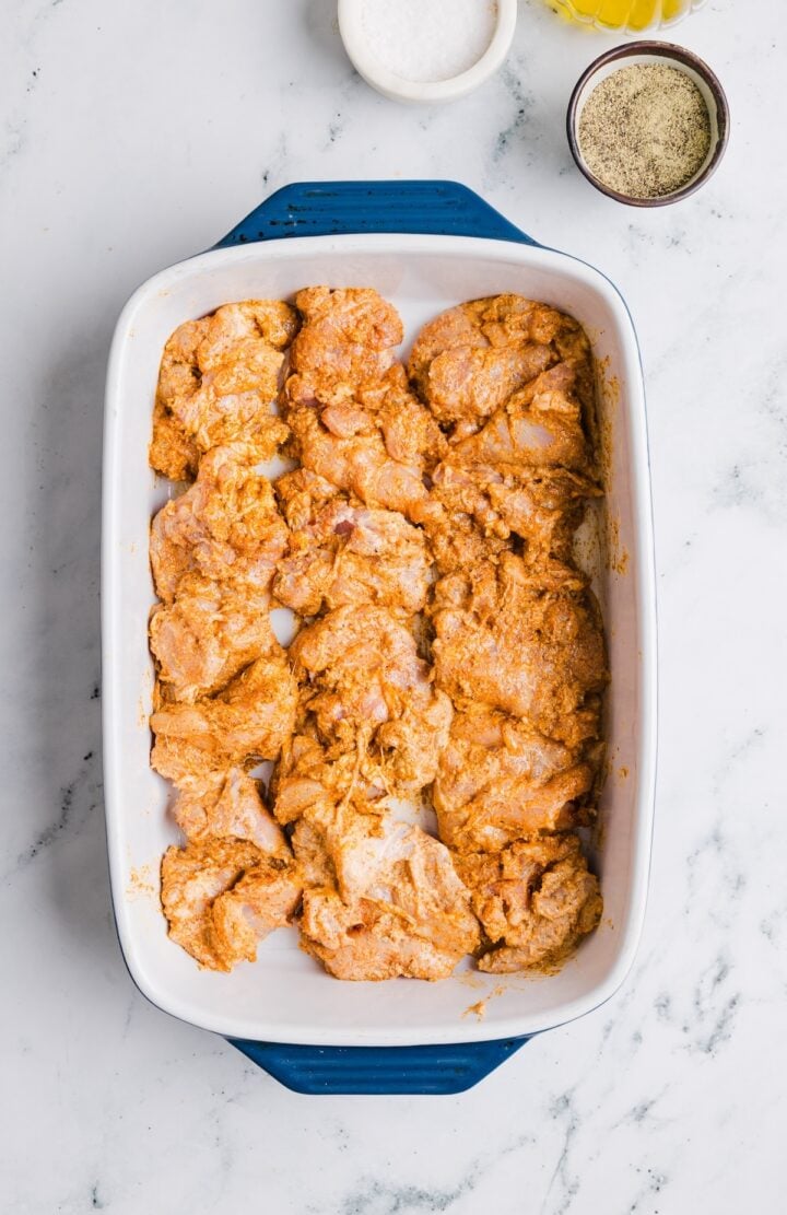 Raw chicken thighs spread out in a large baking dish