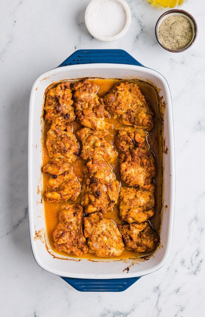 Cooked meal prep chicken thighs in a large ceramic baking dish