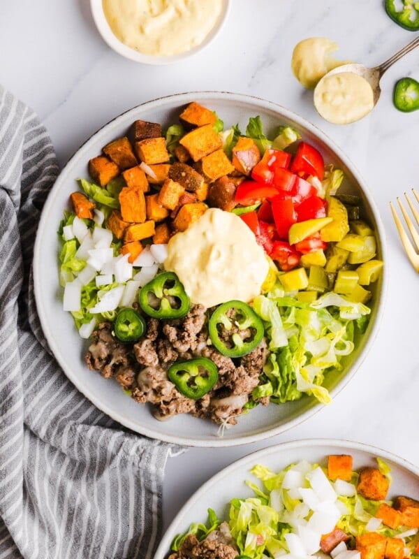 Overhead photo of two sweet potato burger bowls with healthy big mac sauce and other toppings