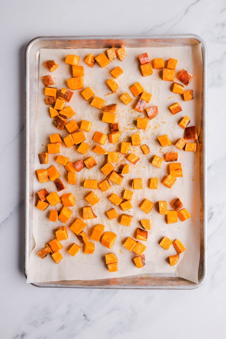 cubed roasted sweet potatoes on a parchment-lined sheet pan