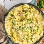 Chicken alfredo spaghetti squash in a pan, topped with red pepper flakes and parsley