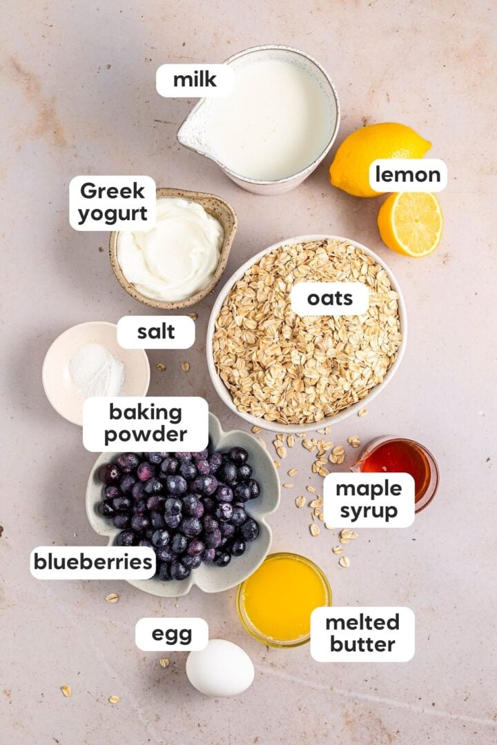 labeled photo of all ingredients for lemon blueberry baked oatmeal, displayed in small bowls on a kitchen counter