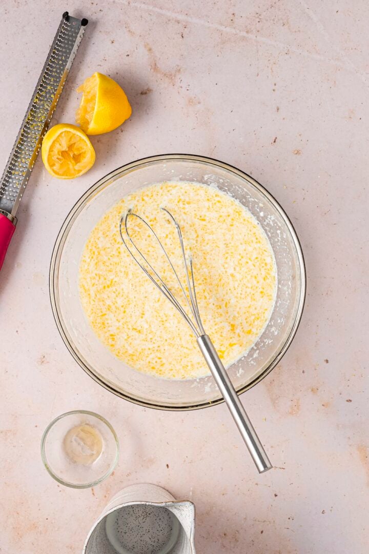Wet ingredients for lemon blueberry baked oatmeal whisked in a large glass bowl