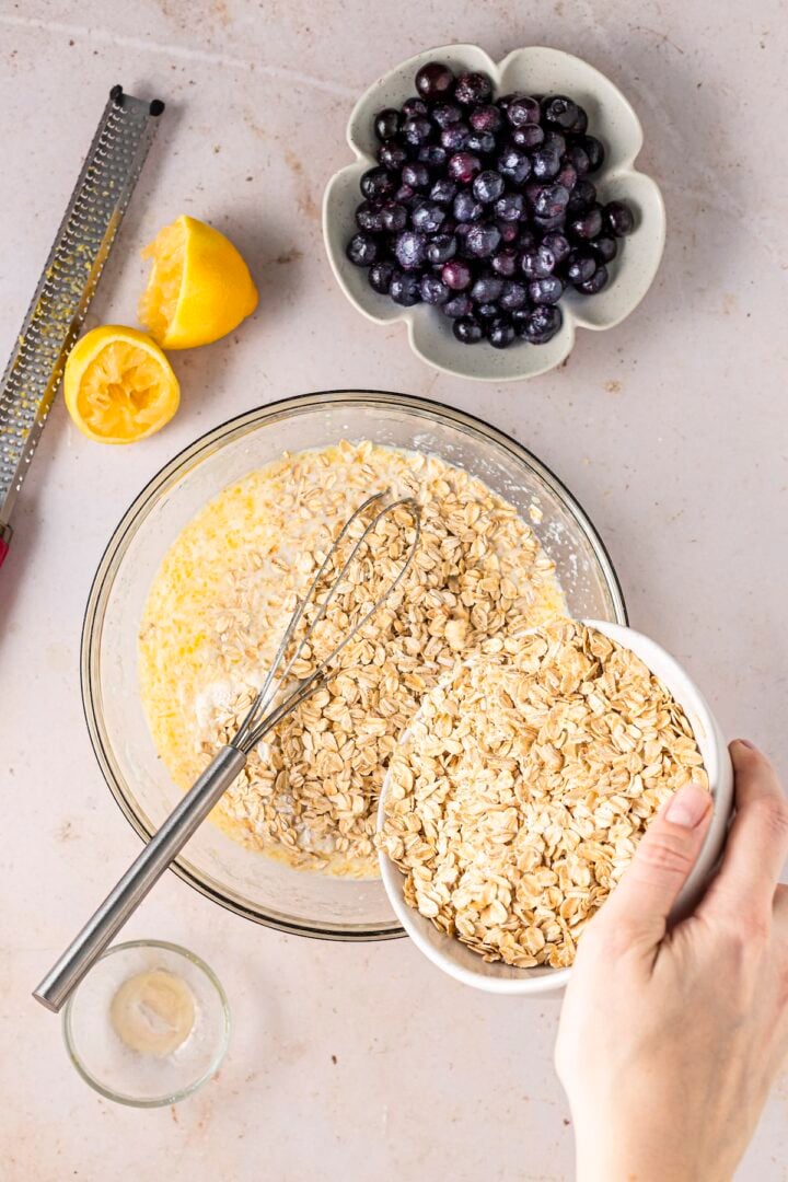 Oats being stirred into wet ingredients for lemon blueberry baked oatmeal