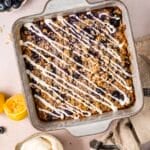 Lemon blueberry baked oatmeal in a baking dish, topped with a lemon yogurt drizzle