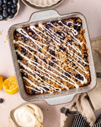 Lemon blueberry baked oatmeal in a baking dish, topped with a lemon yogurt drizzle