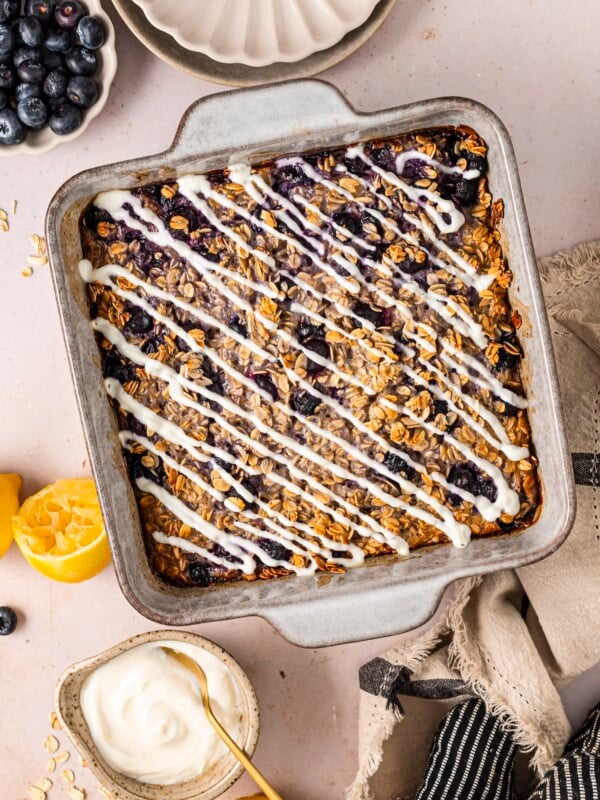 Lemon blueberry baked oatmeal in a baking dish, topped with a lemon yogurt drizzle