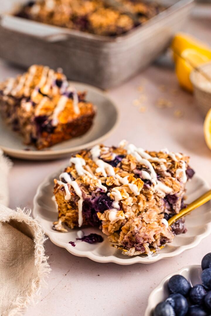 Slice of lemon blueberry baked oatmeal with lemon drizzle on a small plate