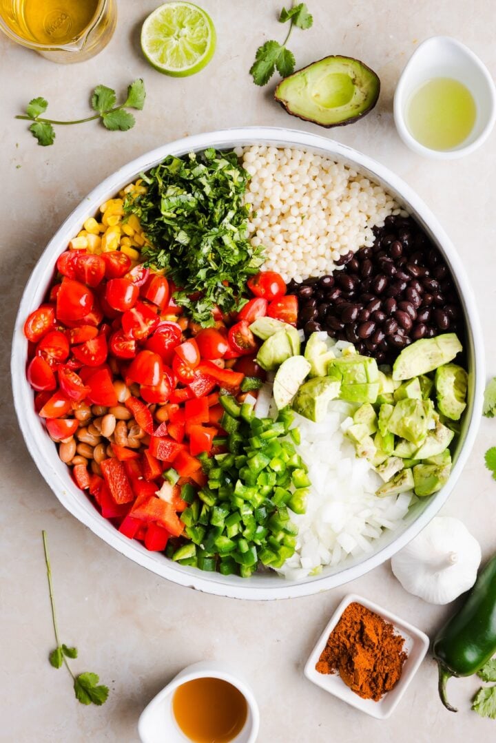 Ingredients for cowboy caviar couscous salad added to a large bowl, unmixed