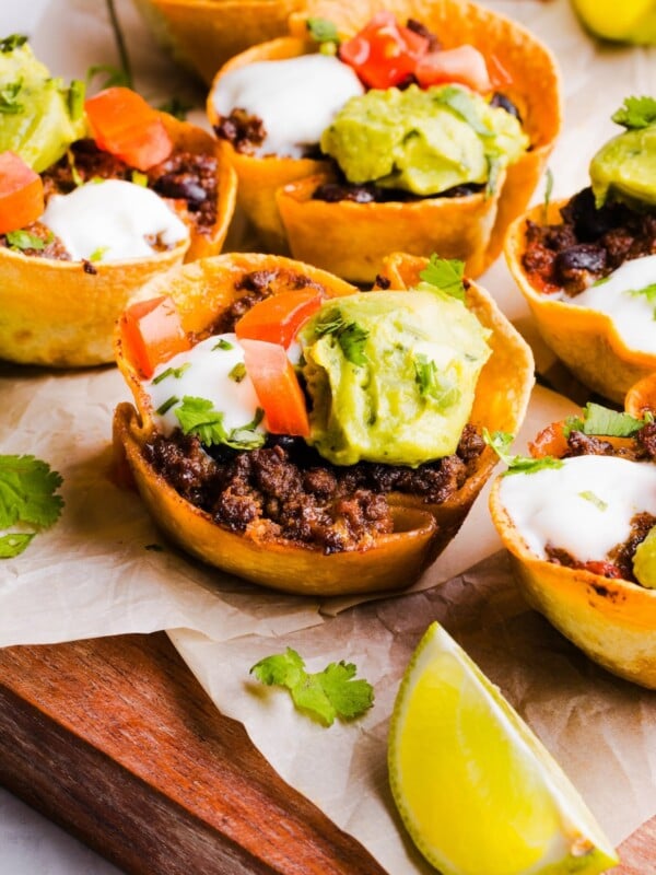 Taco cups topped with tomato, guacamole, and sour cream