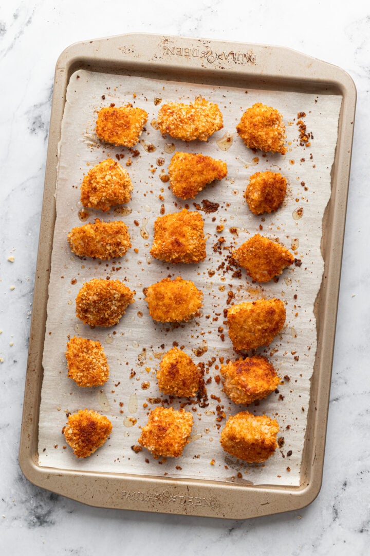 Baked panko chicken nuggets on a lined sheet pan