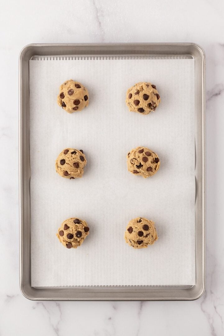 Cookie dough spooned onto a parchment-lined sheet pan