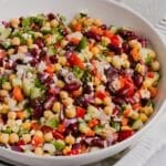 Greek bean salad mixed in a large white bowl