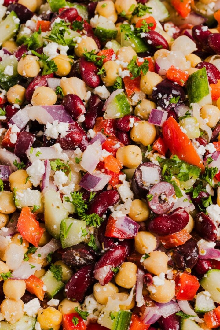 Close-up photo of Greek Bean Salad tossed with vinaigrette in a large mixing bowl